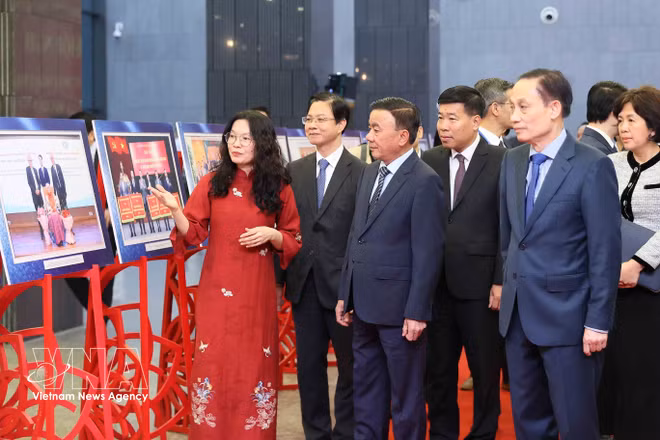 Tran Cam Tu, miembro del Buró Político y miembro permanente del Secretariado del Comité Central del Partido, junto a delegados que visitan una exposición que muestra imágenes destacadas de la diplomacia entre pueblos en 2025. Foto: VNA