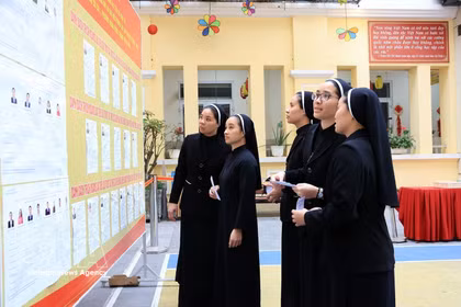 Monjes de la Congregación de las Hermanas de la Caridad de la Santa Cruz consultan la lista de candidatos en el colegio electoral No. 1, barrio de Hoan Kiem, Hanoi. Foto: VNA
